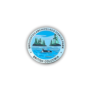 A circular pin badge featuring the Broughton Archipelago Marine Park in British Columbia, Canada. The design shows a blue ocean with an orca whale, two green islands with pine trees, and a light blue sky, all enclosed by a white border with black text reading 'BROUGHTON ARCHIPELAGO MARINE PARK' and 'BRITISH COLUMBIA'.