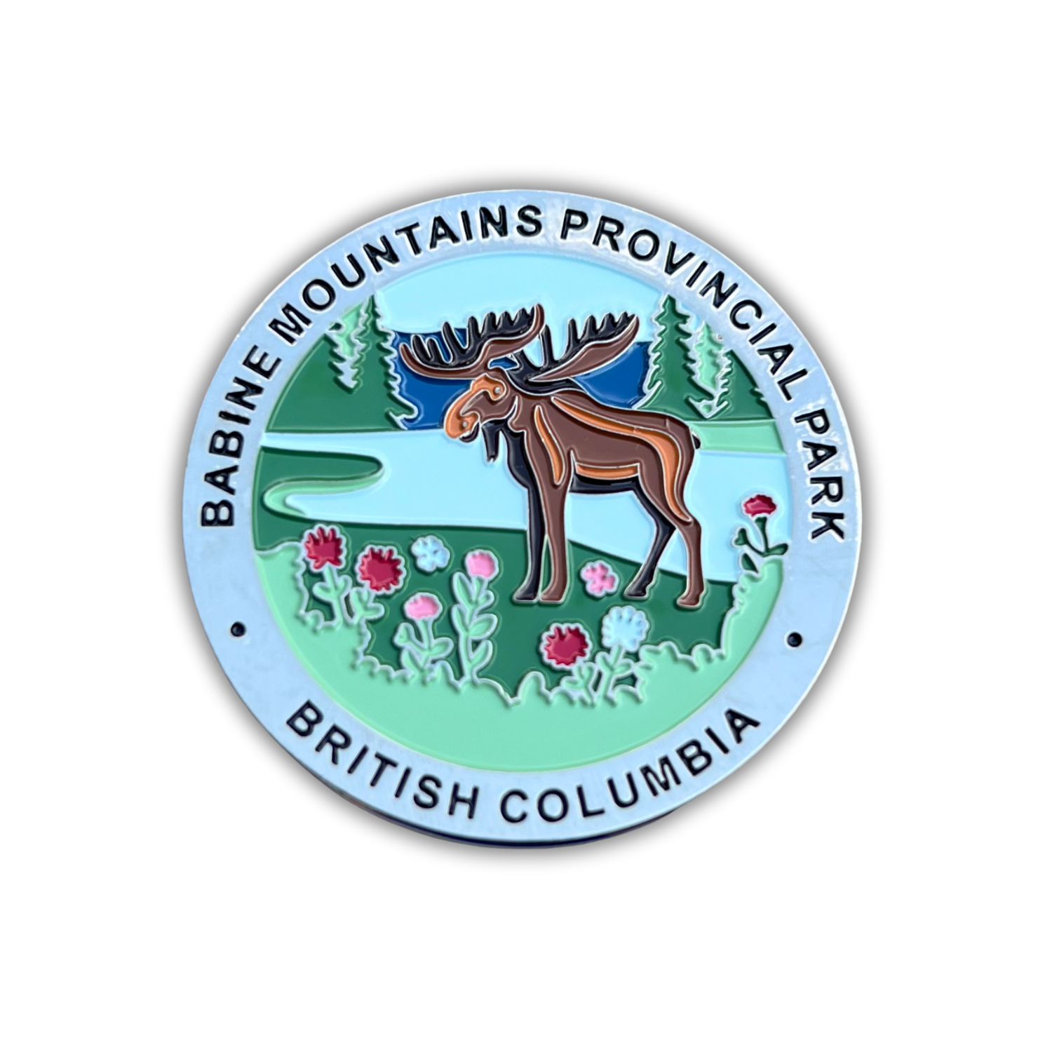 A circular enamel-style Magnet for Babine Mountains Provincial Park, British Columbia, featuring a moose, trees, flowers, and a light blue border with black text.