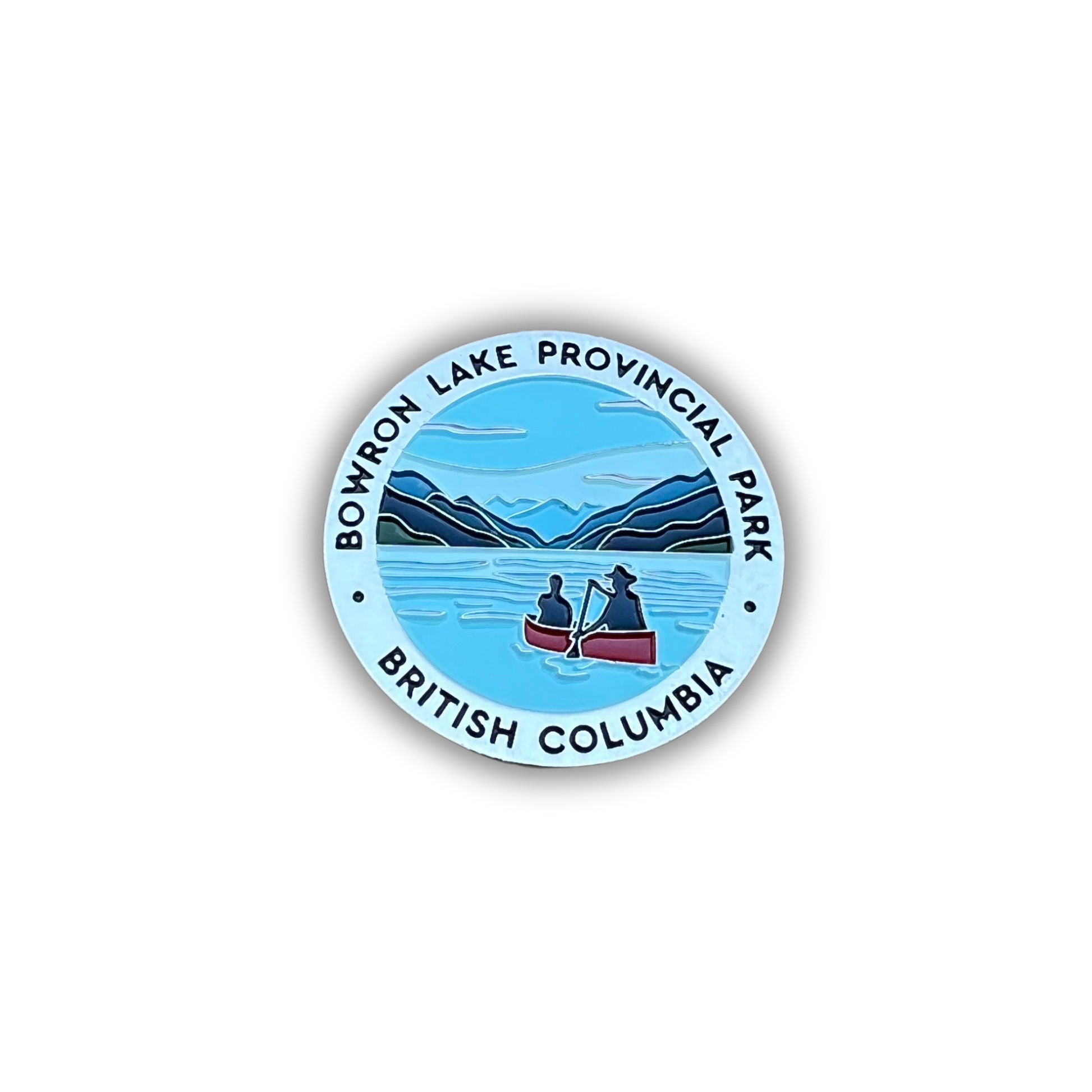 A circular enamel pin featuring a scenic illustration of Bowron Lake Provincial Park in British Columbia, with two people rowing a red canoe on blue water, surrounded by a light blue border with black text.