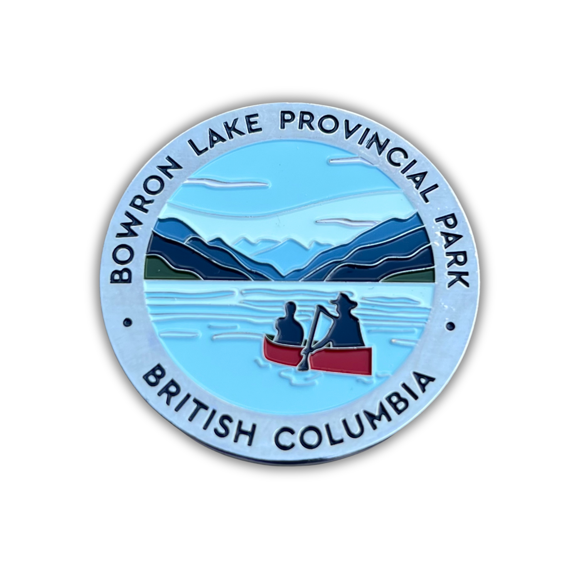 A circular enamel-style park magnet for Bowron Lake Provincial Park in British Columbia, featuring a light blue lake, dark blue mountains, and two people rowing in a red canoe, with the park name around the border.