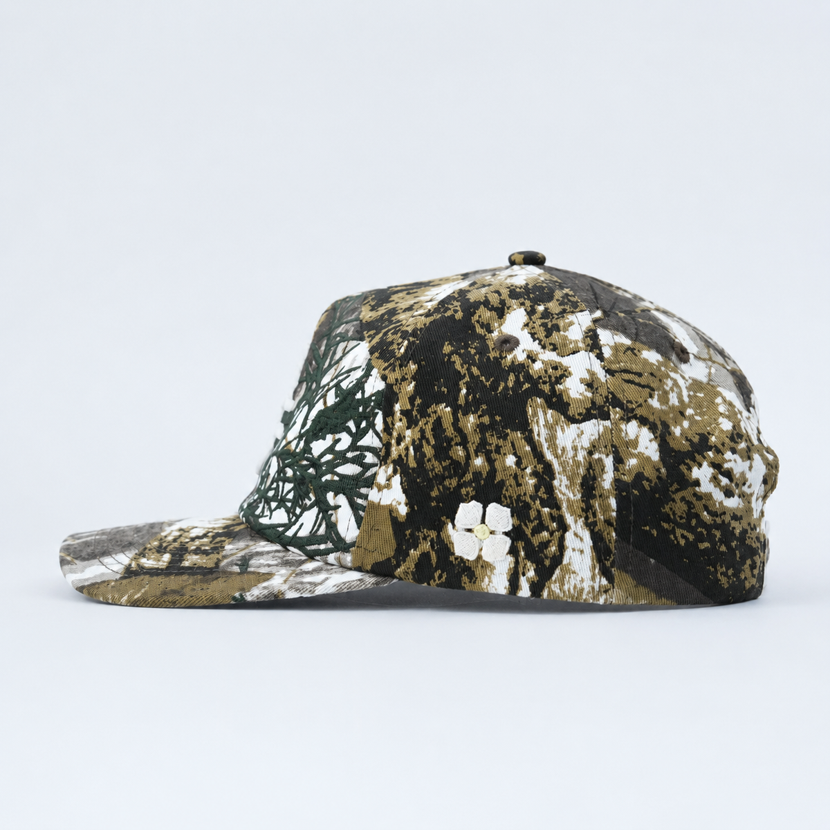 A structured baseball cap featuring a realistic woodland camouflage pattern with brown, black, green, and white tones, shown from a side profile on a light gray background.
