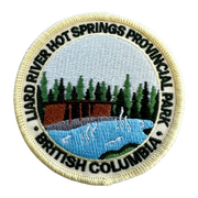 An embroidered circular patch for Liard River Hot Springs Provincial Park in British Columbia, featuring a scenic landscape with a cabin, pine trees, blue water, and black text on a cream background.