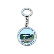 A round metal keychain featuring the Myra-Bellevue Provincial Park emblem from British Columbia, Canada. The silver-tone keychain has a circular pendant with a light blue background, green and dark blue mountain illustration, and black text reading 'MYRA-BELLEVue PROVINCIAL PARK' and 'BRITISH COLUMBIA'.