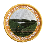 An embroidered circular patch for Myra-Bellevue Provincial Park, British Columbia, featuring a landscape design with green hills, a lake, and a fence, surrounded by a gold border with white text.