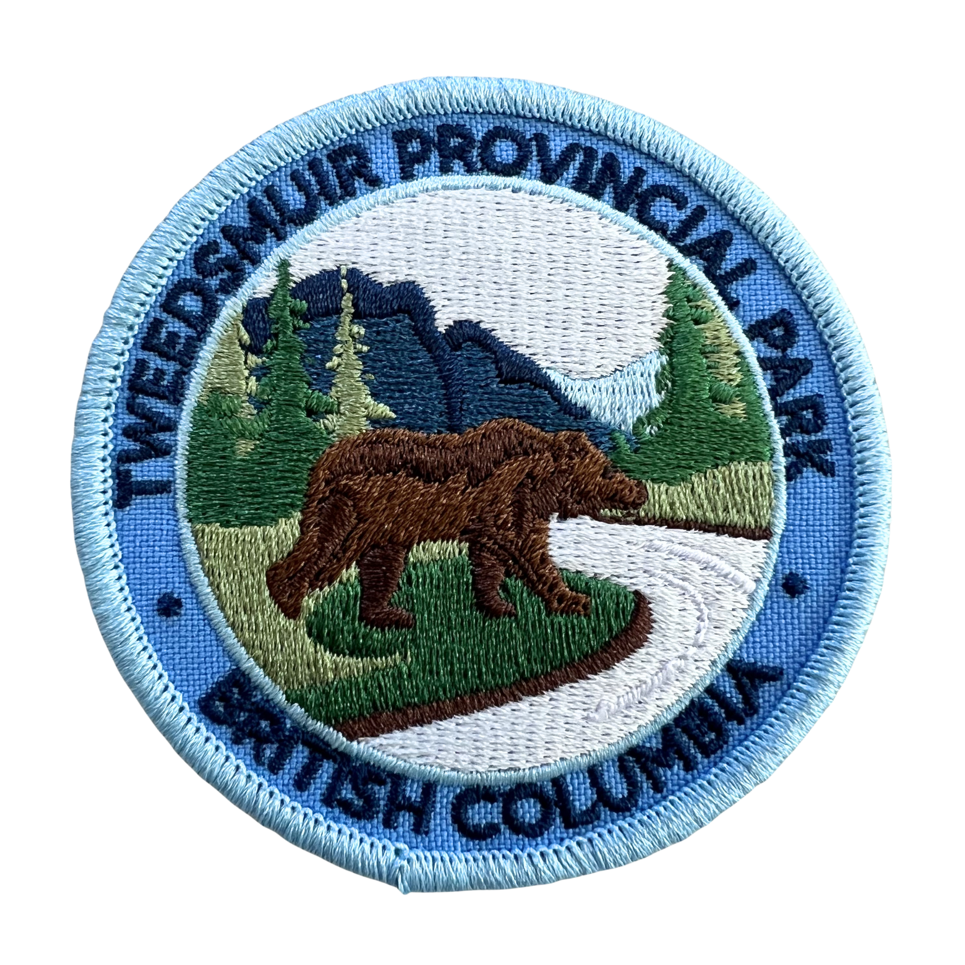 An embroidered circular patch for Tweedsmuir Provincial Park, British Columbia, featuring a brown grizzly bear, green pine trees, blue mountains, and a light blue border with dark blue text.